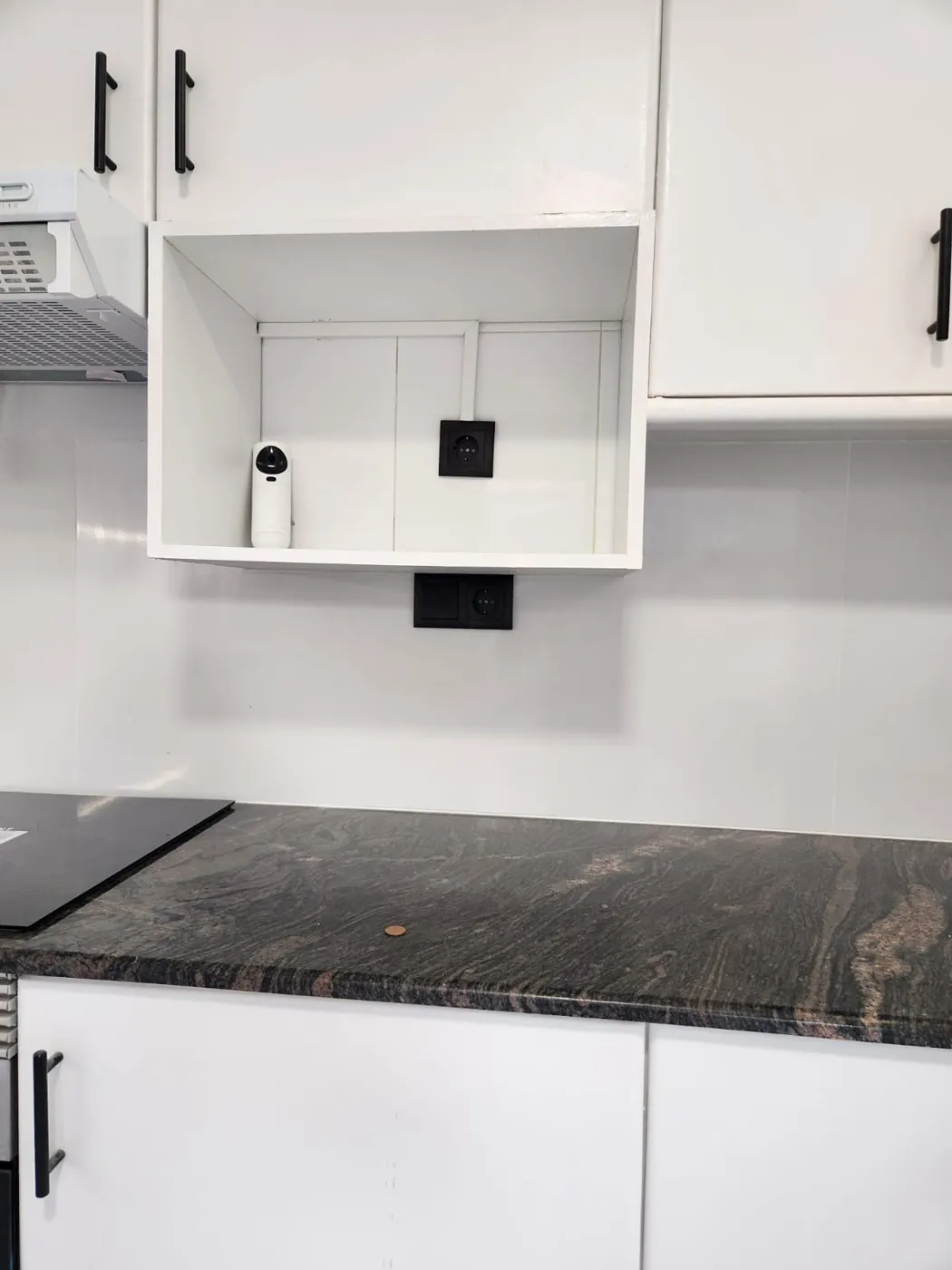 Cocina con muebles blancos, tiradores negros y encimera de granito