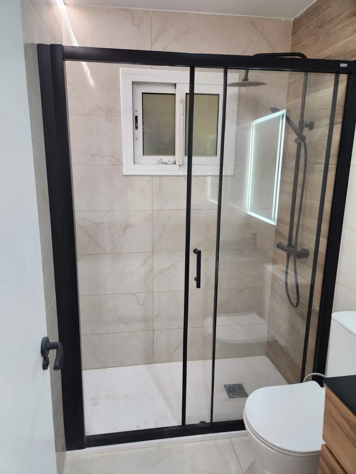 Reforma de baño con mampara de perfilería negra y plato de ducha blanco en Barcelona