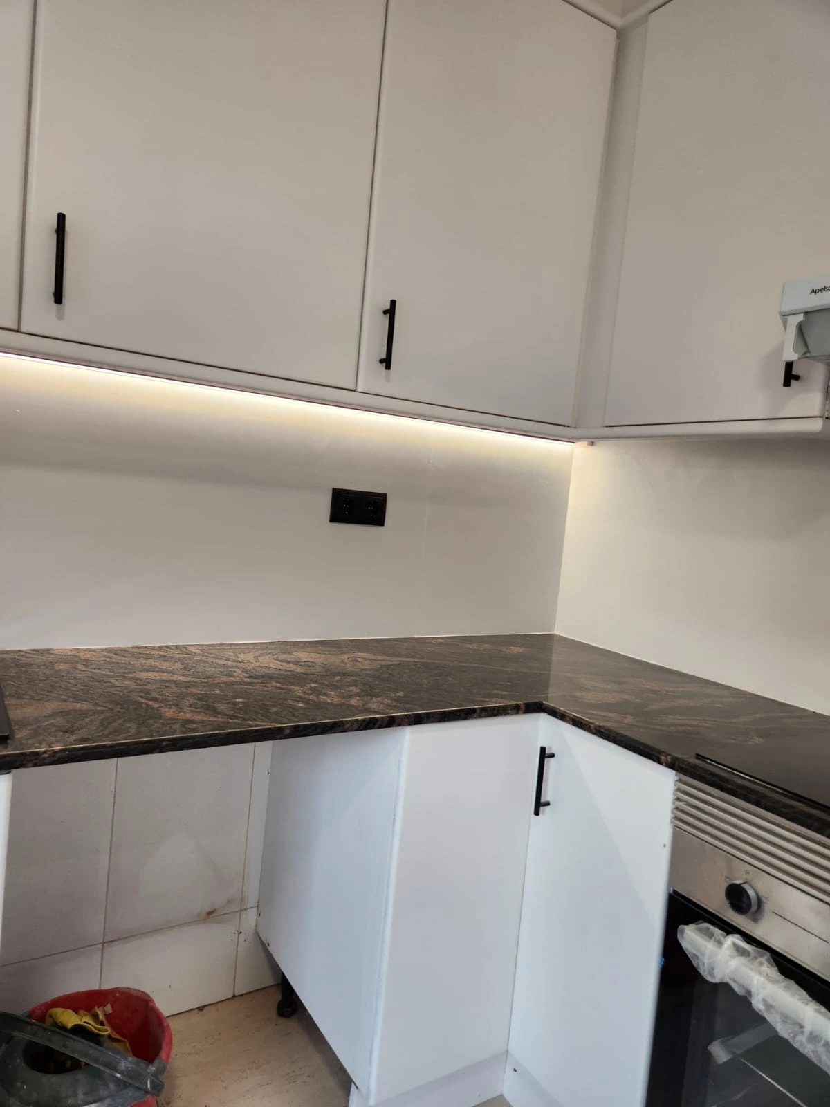 Reforma de cocina con encimera de granito oscuro y muebles blancos con tiradores negros en Barcelona