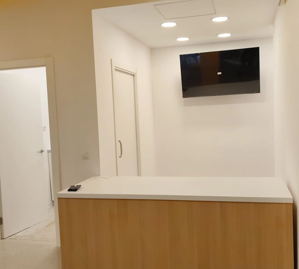 Reforma integral de local con mostrador de madera, encimera blanca y televisión en pared, Barcelona