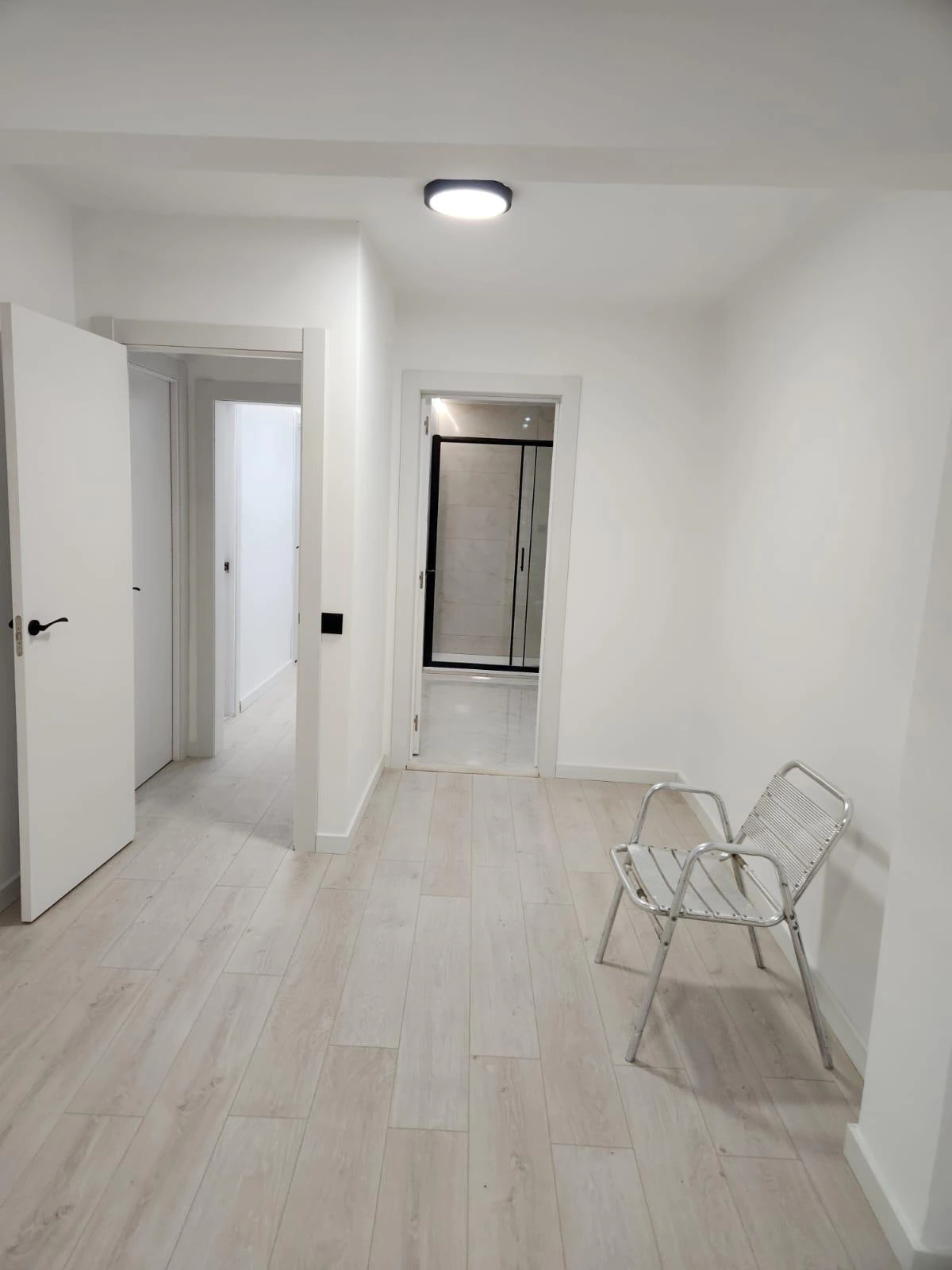 Reforma integral de vivienda con suelo laminado claro, paredes blancas y puertas de madera en Barcelona
